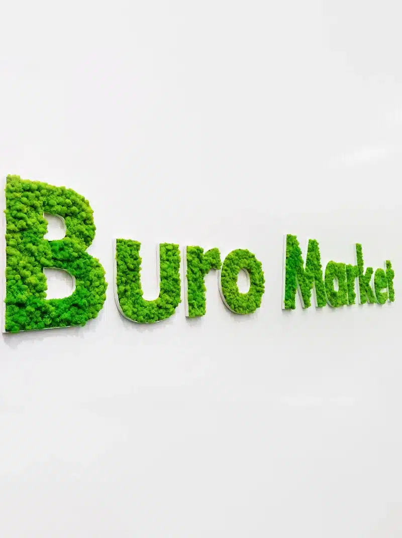 Green moss-covered Buro Market logo on white wall.